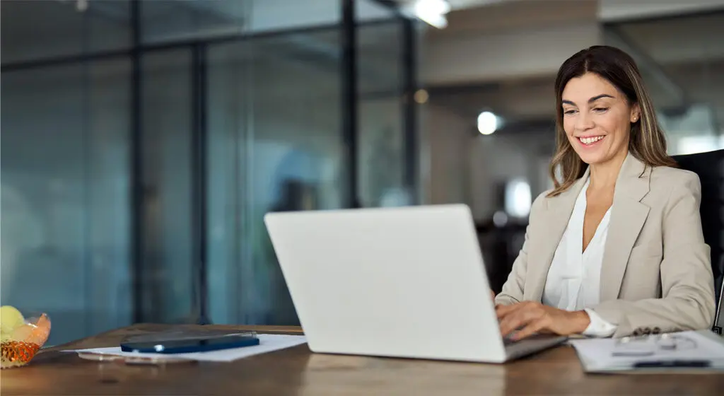 business woman smiling and working on a computer in an office setting