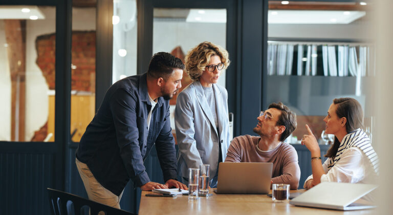 Group of people engaged in conversation in a corporate meeting room.