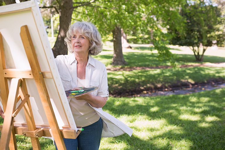 a senior painting in the garden