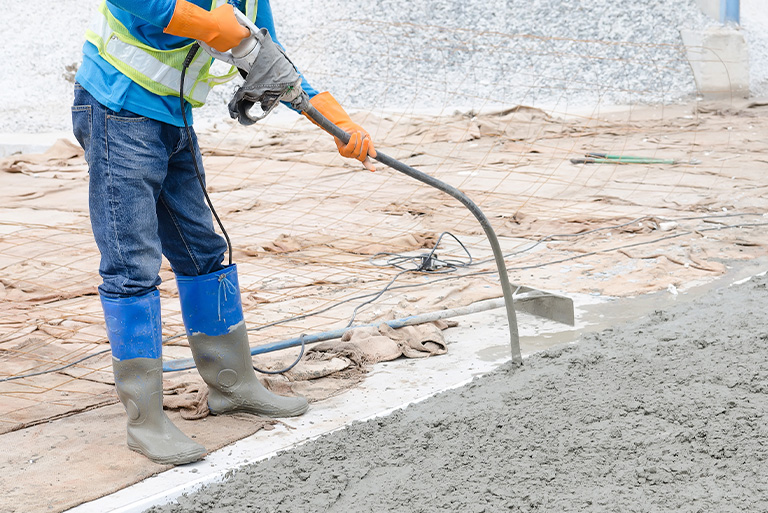 a construction worker using a machine to get bubbles out of cement