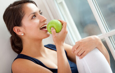 woman about to take a bite of a green apple