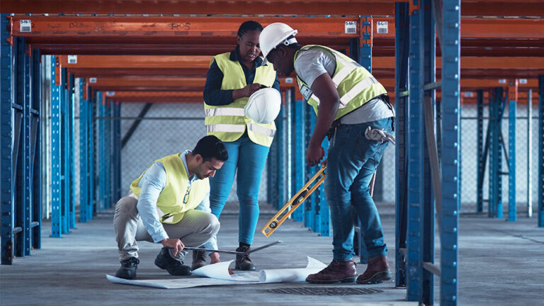 Construction workers reviewing blueprint plans at a job site