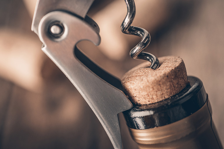 a close up of opening a wine bottle with a corkscrew