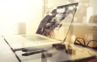 Laptop, pen and glasses sitting on top of a desk