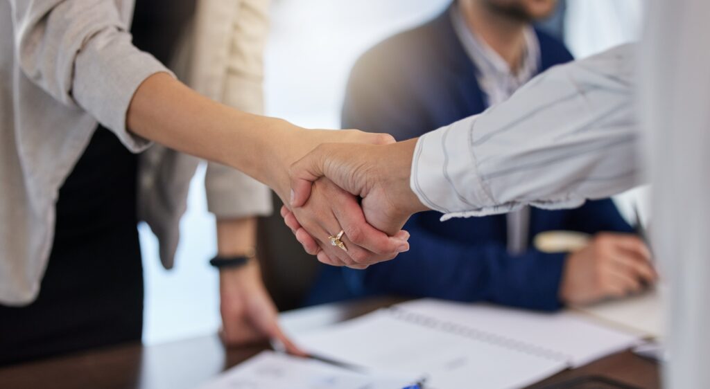 Close-up of man and women shaking hands in an office.