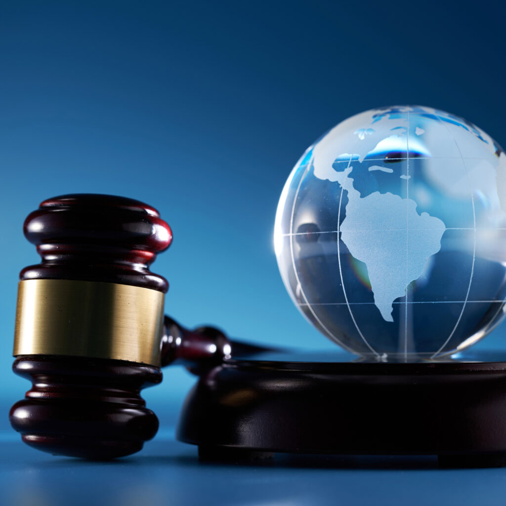 Glass globe sits on a table next to a gavel indicating law and global compliance