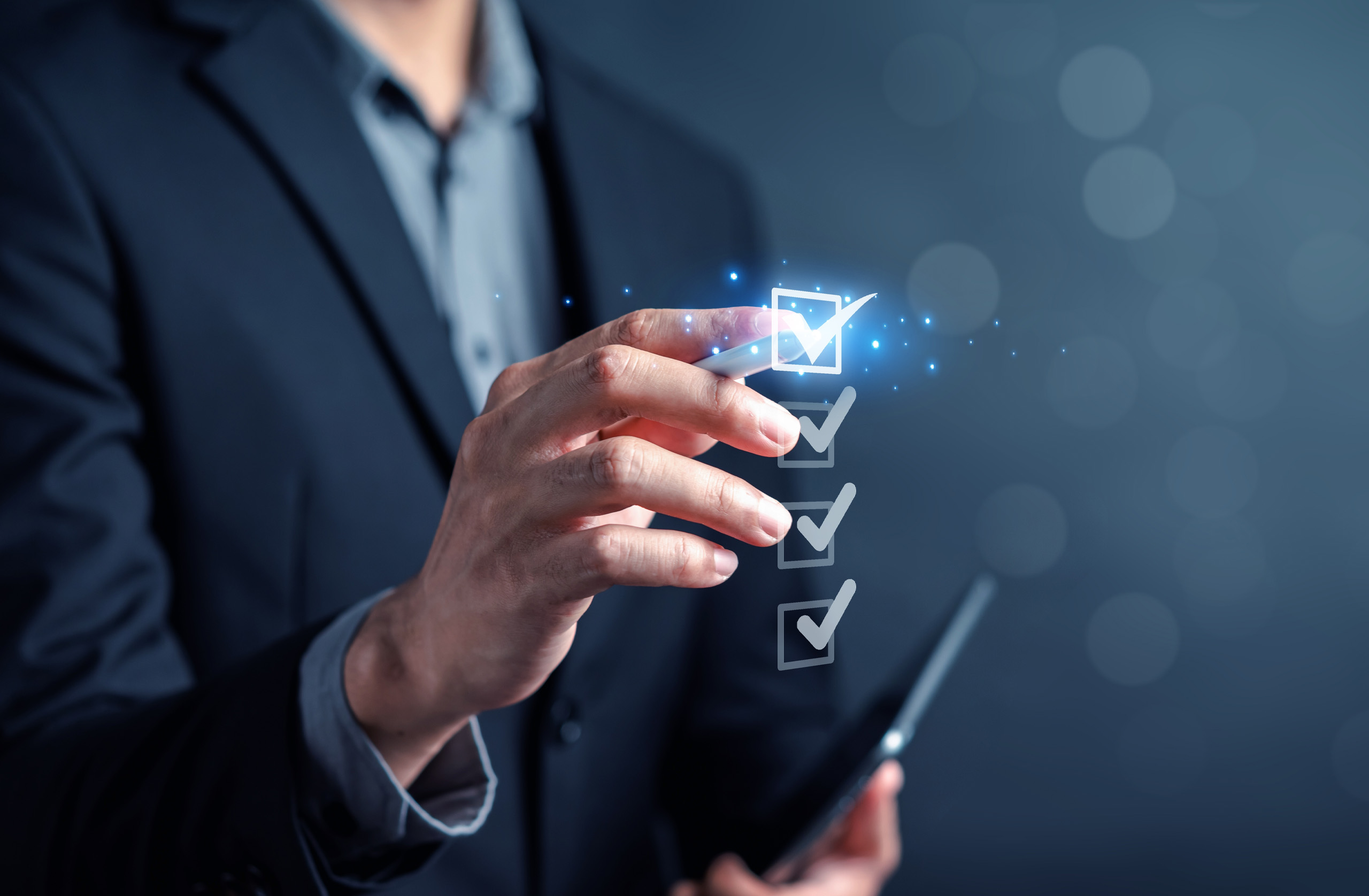 Business man holds his hand up to check off a digital to-do list