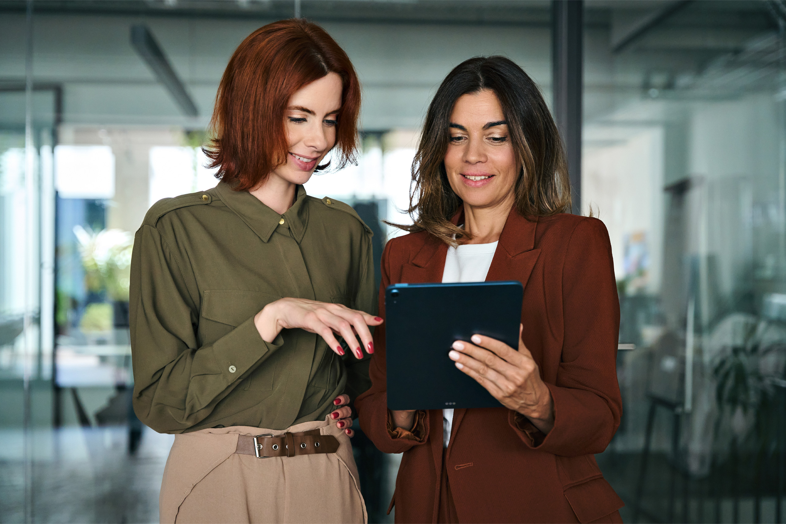 Two business women talk over a tablet discussing e-invoicing compliance